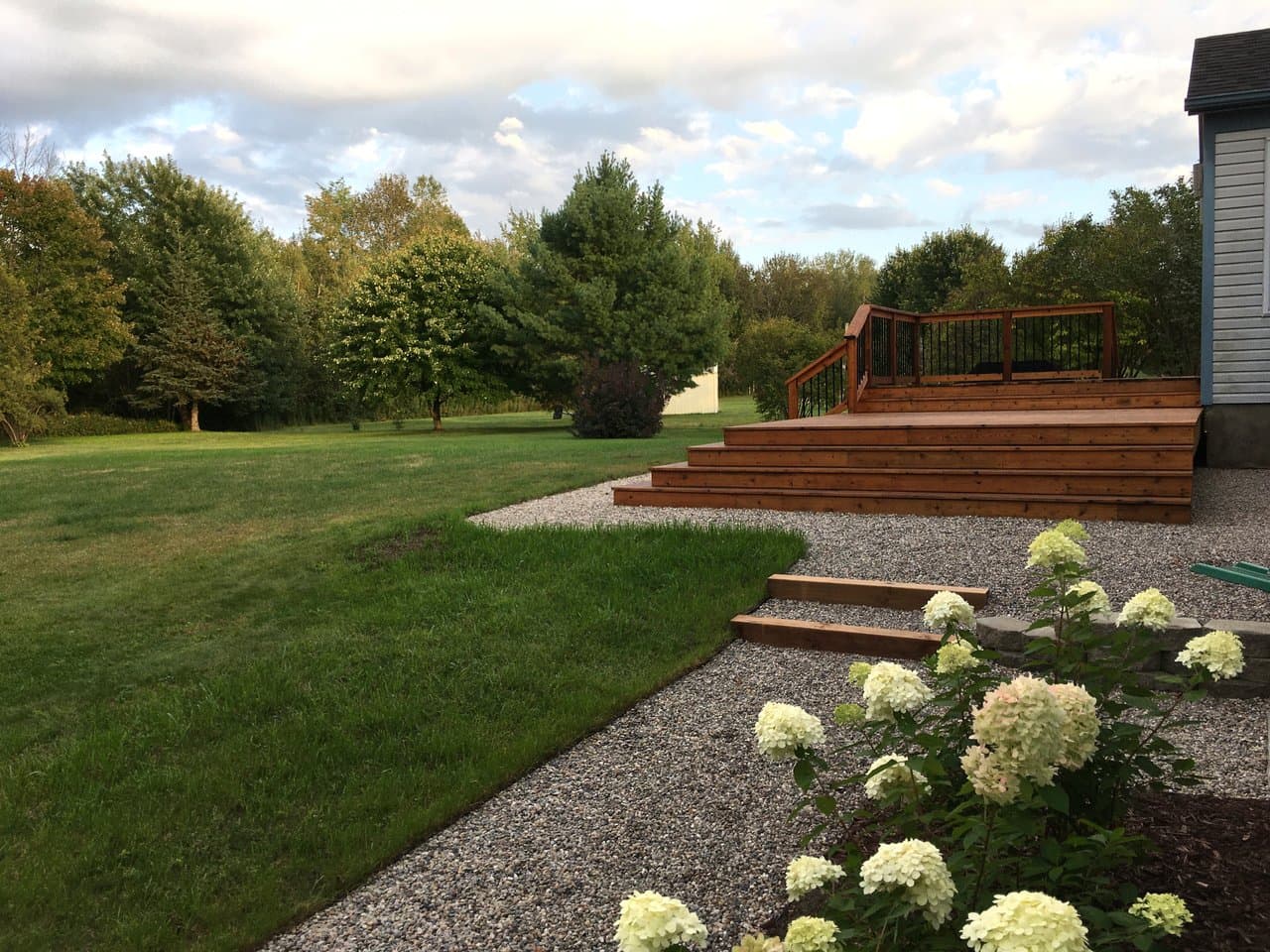 A finished multi-level cedar back deck with wide steps beside a blue-grey house.